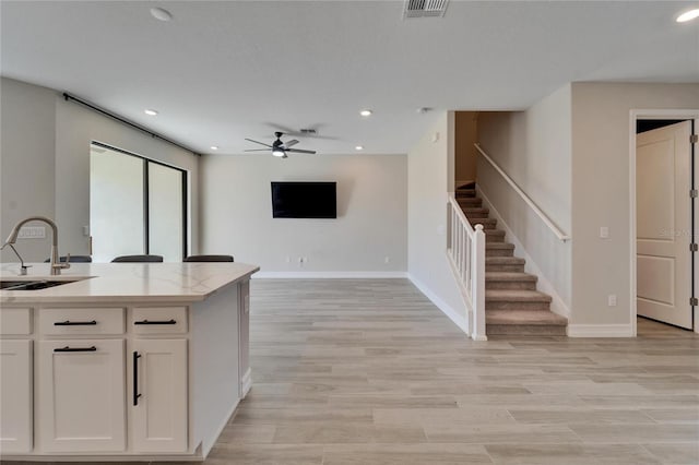 kitchen featuring light hardwood / wood-style flooring, white cabinetry, ceiling fan, and sink