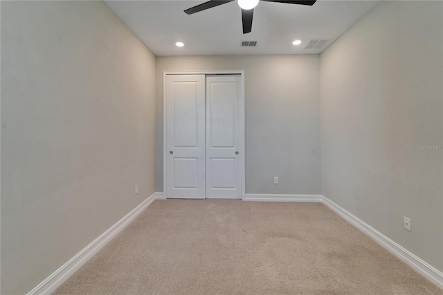 unfurnished bedroom with light carpet, a closet, and ceiling fan