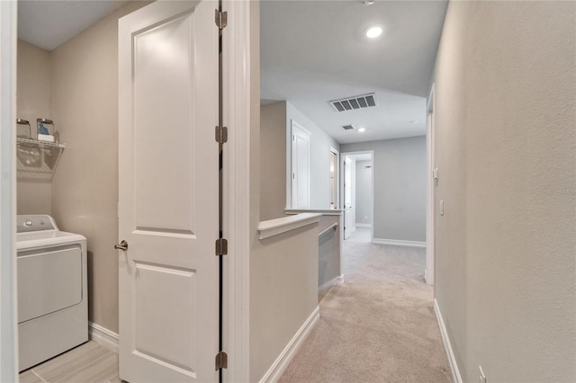 corridor with light carpet and washer / clothes dryer