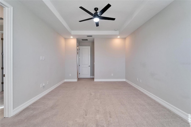 unfurnished room with light carpet, a tray ceiling, and ceiling fan