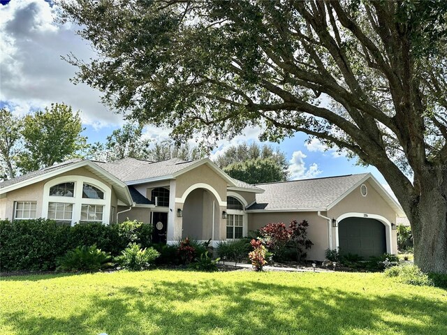 ranch-style house with stucco siding, a front yard, and an attached garage