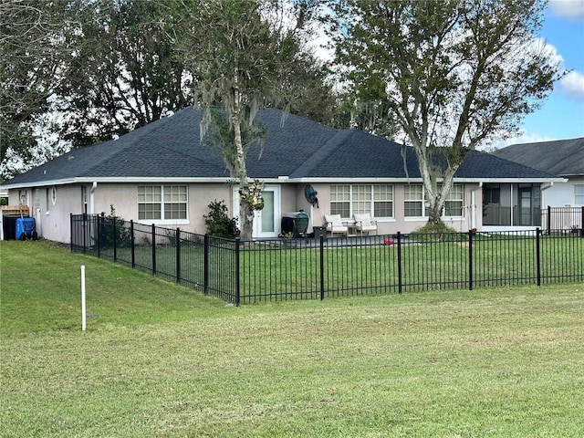 rear view of property featuring stucco siding, fence, a yard, and a shingled roof