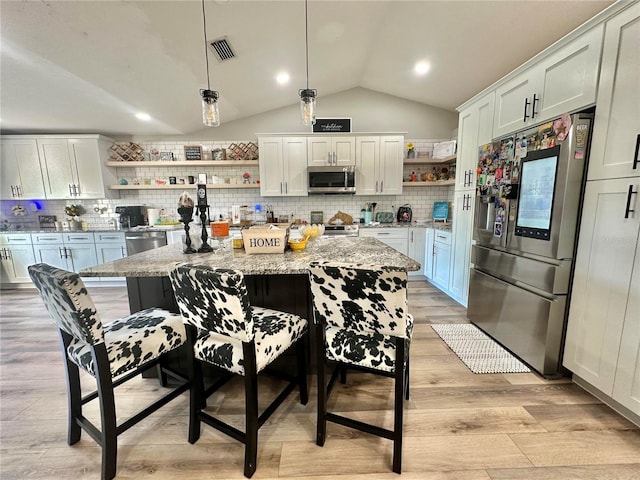 kitchen featuring light wood-style flooring, stainless steel appliances, open shelves, vaulted ceiling, and visible vents