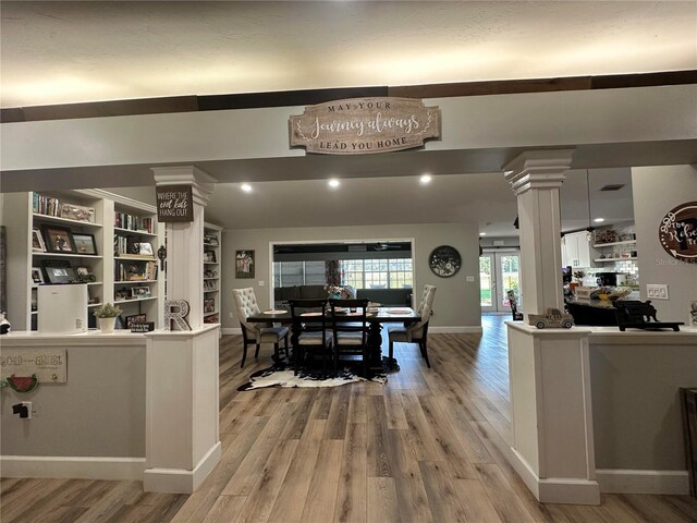 kitchen with light wood finished floors, decorative columns, open floor plan, and baseboards