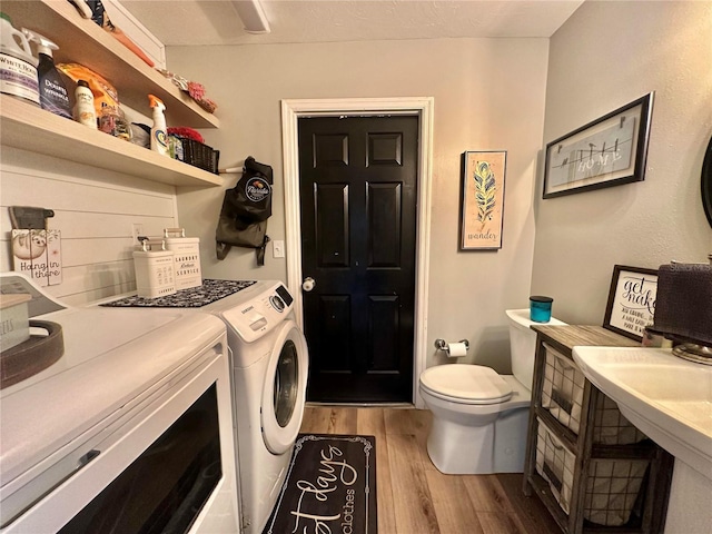 clothes washing area featuring washer and dryer, light wood-style flooring, and laundry area