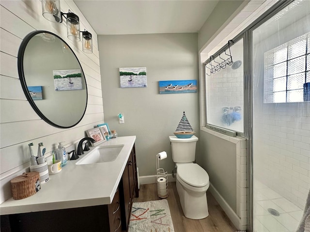 full bath featuring a shower stall, vanity, toilet, baseboards, and wood finished floors