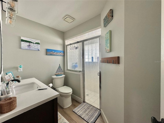 bathroom featuring vanity, toilet, a stall shower, baseboards, and wood finished floors