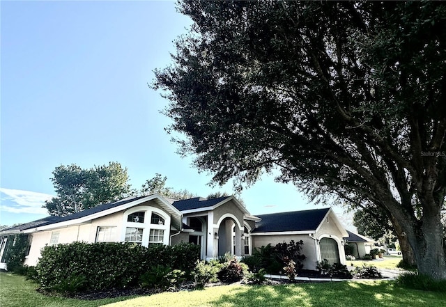 ranch-style home featuring a front lawn and stucco siding
