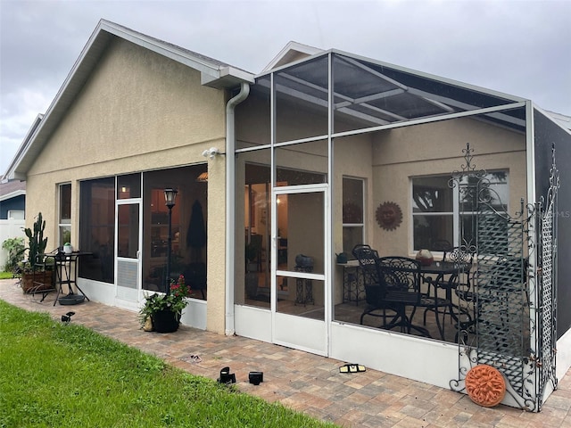 back of property with a patio and glass enclosure