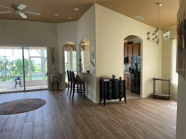 kitchen with ceiling fan with notable chandelier, hanging light fixtures, hardwood / wood-style floors, and black fridge with ice dispenser