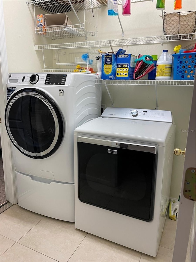 clothes washing area featuring washer and clothes dryer and light tile patterned floors