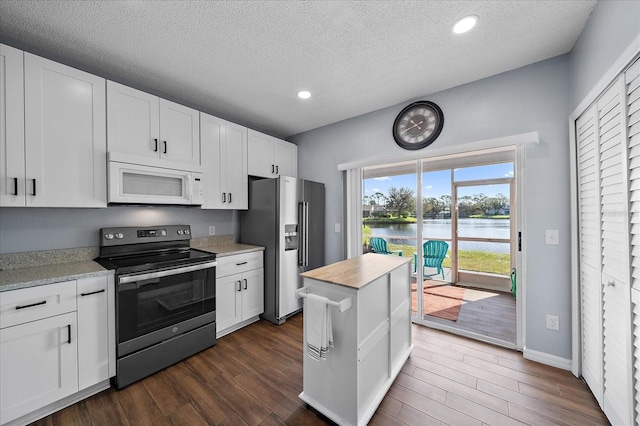 kitchen featuring appliances with stainless steel finishes, white cabinetry, a water view, and dark hardwood / wood-style flooring