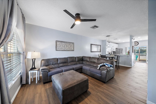 living room with ceiling fan, a textured ceiling, and dark hardwood / wood-style flooring