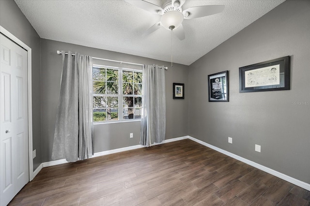 unfurnished bedroom with a closet, ceiling fan, vaulted ceiling, and dark hardwood / wood-style flooring