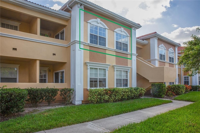 view of side of home featuring a lawn and a balcony