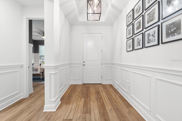 interior space with ceiling fan with notable chandelier, light hardwood / wood-style flooring, and decorative columns