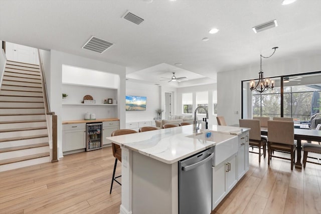 kitchen with a center island with sink, wine cooler, white cabinetry, sink, and stainless steel dishwasher