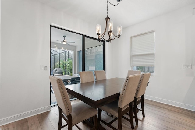 dining room with hardwood / wood-style floors and ceiling fan with notable chandelier