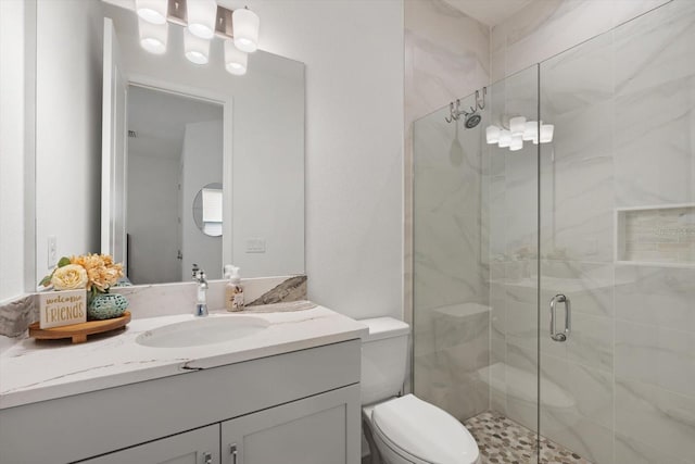 bathroom with a shower with shower door, vanity, and toilet