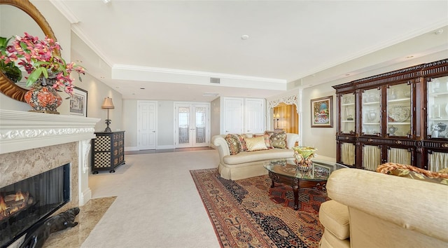 living room with light colored carpet, french doors, a high end fireplace, and ornamental molding