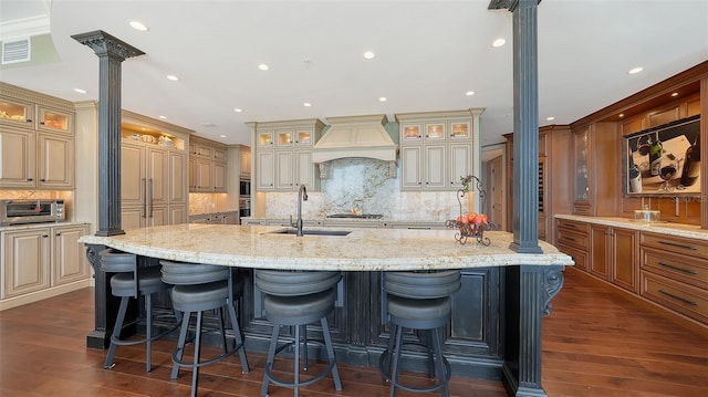 kitchen with a spacious island, dark wood-type flooring, a breakfast bar area, and decorative columns