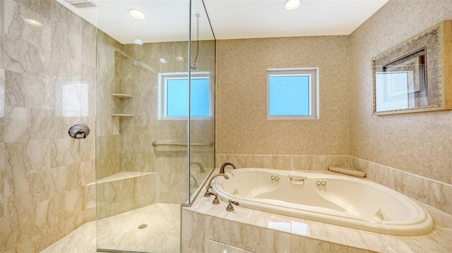 bathroom with shower with separate bathtub and a wealth of natural light