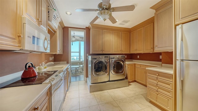 clothes washing area with crown molding, light tile patterned floors, sink, washing machine and clothes dryer, and ceiling fan