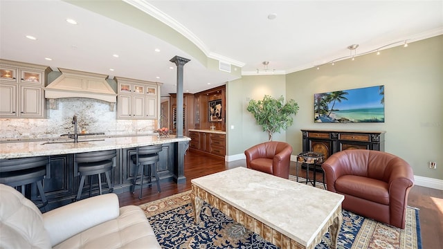 living room with dark hardwood / wood-style flooring, decorative columns, sink, and crown molding