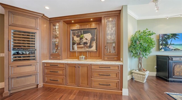 bar featuring dark wood-type flooring, track lighting, light stone counters, and crown molding