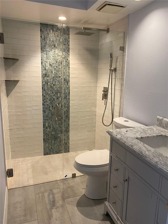 bathroom with tile patterned flooring, vanity, toilet, and a shower with shower door