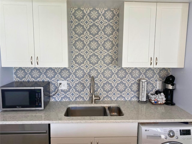 kitchen featuring light stone countertops, appliances with stainless steel finishes, sink, white cabinets, and washer / clothes dryer