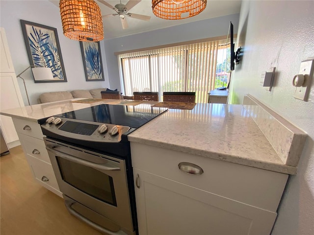 kitchen featuring ceiling fan, light stone counters, white cabinetry, and stainless steel range with electric cooktop