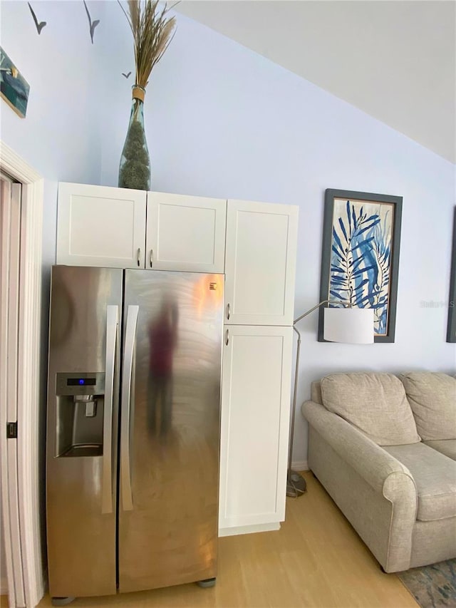 kitchen with vaulted ceiling, white cabinetry, light hardwood / wood-style flooring, and stainless steel refrigerator with ice dispenser