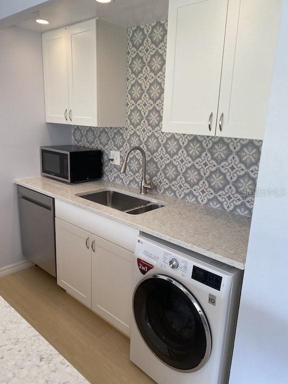 kitchen featuring appliances with stainless steel finishes, washer / clothes dryer, white cabinetry, and light hardwood / wood-style flooring