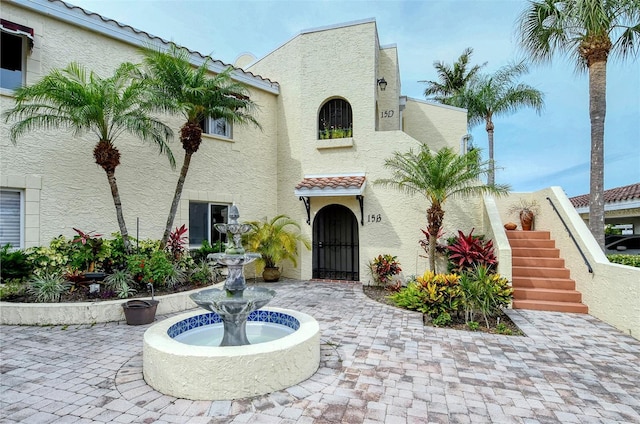 mediterranean / spanish-style home featuring stucco siding, a tiled roof, and stairs