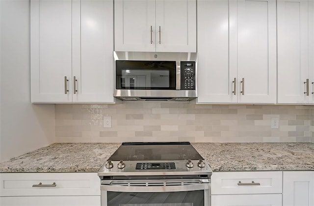 kitchen featuring stainless steel appliances, white cabinets, tasteful backsplash, and light stone counters