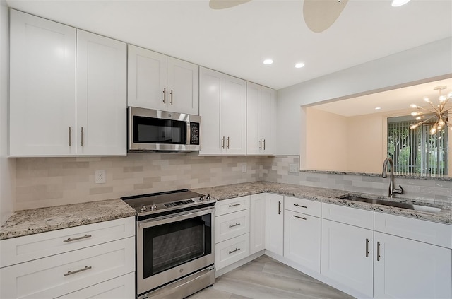kitchen with appliances with stainless steel finishes, a sink, a chandelier, white cabinetry, and recessed lighting