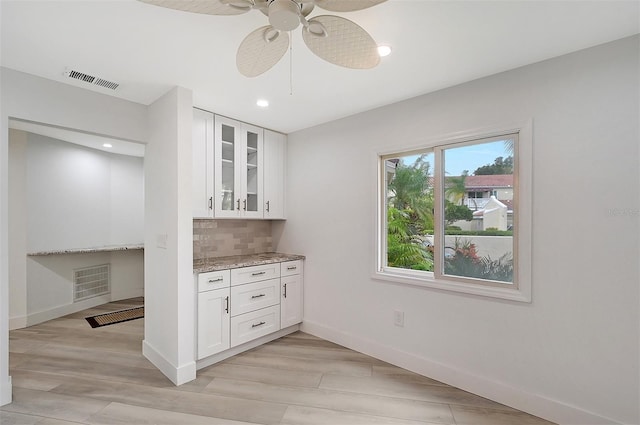 kitchen with white cabinetry, light stone counters, light hardwood / wood-style floors, and ceiling fan