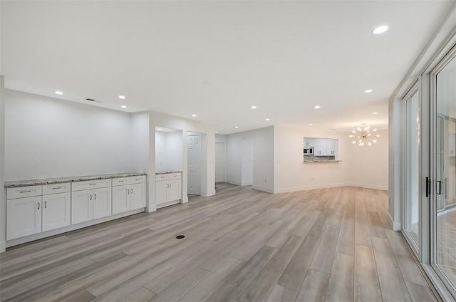 unfurnished room with light wood-type flooring, recessed lighting, baseboards, and a chandelier