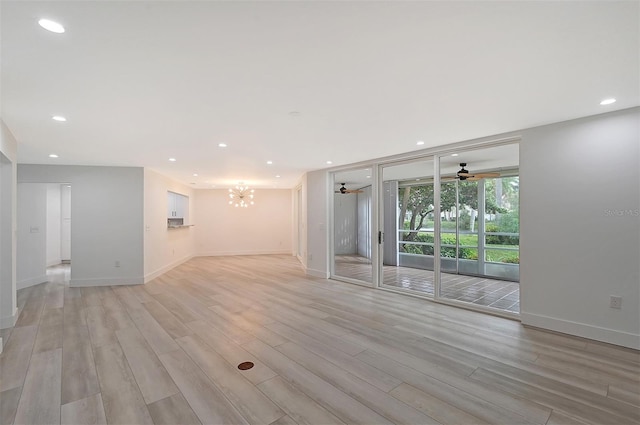 unfurnished living room with a ceiling fan, light wood finished floors, a chandelier, recessed lighting, and a wall of windows