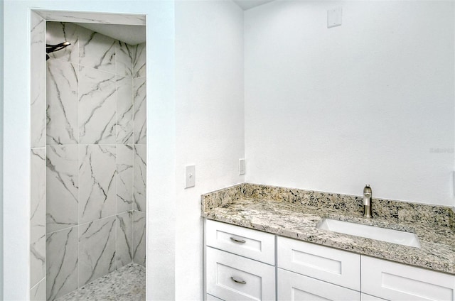 bathroom featuring a marble finish shower and vanity