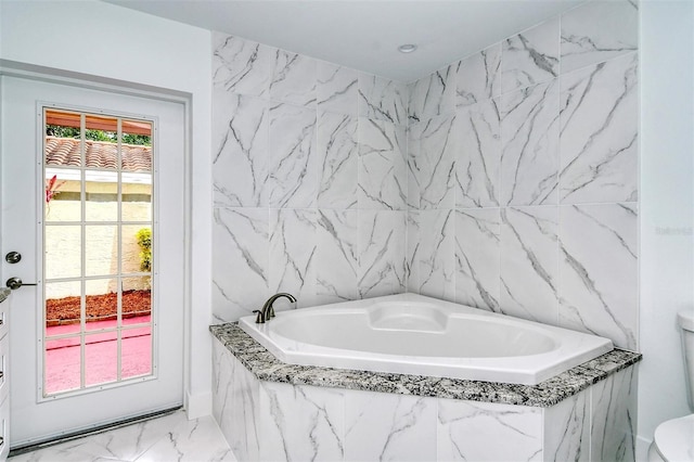 bathroom with marble look tile flooring, a bath, and toilet