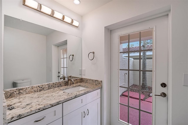 bathroom with toilet, vanity, and recessed lighting