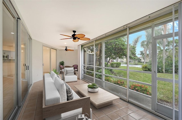 sunroom / solarium with tile patterned floors, healthy amount of natural light, a ceiling fan, and a water view