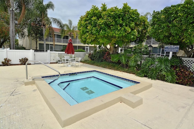 view of pool with fence, a community hot tub, and a patio