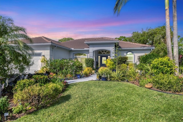 mediterranean / spanish home with a lawn and a garage