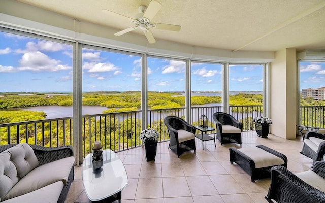 sunroom featuring a water view and ceiling fan