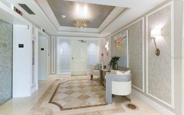 foyer entrance with visible vents, crown molding, and a tray ceiling