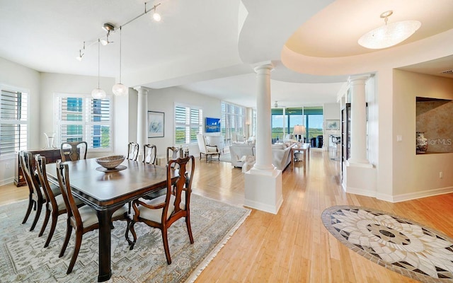 dining room with light hardwood / wood-style floors, ornate columns, and rail lighting