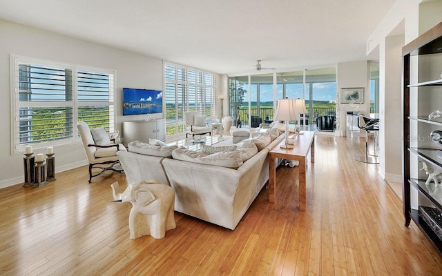 living area featuring baseboards, ceiling fan, a healthy amount of sunlight, and light wood-style flooring